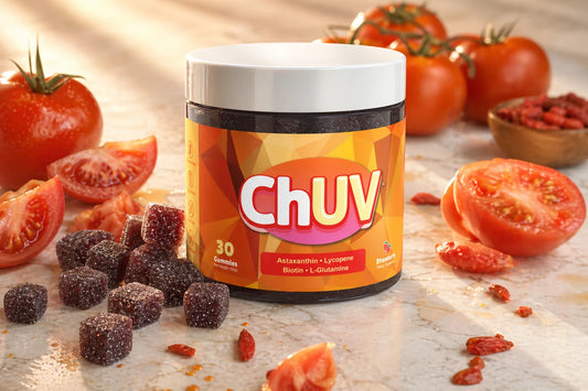 ChUV tanning gummies dark reddish-purple sugar-coated cubes on marble surface beside fresh tomatoes, illustrating a beta carotene-free tanning supplement formula